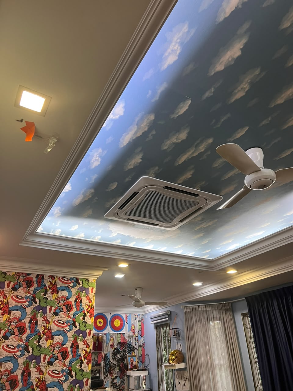 Ceiling cassette aircond under a cloud-painted ceiling